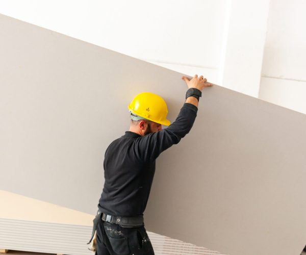 Worker at work in the construction of a plasterboard wall.